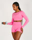 Person wearing a pink athletic outfit holding a dumbbell on a plain background