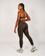 Person wearing a brown sports bra and leggings set on a white background