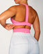 Person wearing a pink sports bra and light grey sweatpants on a plain background