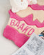 Pink and beige plush toy with 'BAAKO' text on a white surface