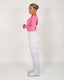Woman wearing a pink top and grey sweatpants on a plain background