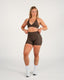 Woman wearing a brown sports bra and shorts set on a white background
