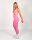 Woman wearing a pink sports bra and leggings set on a white background