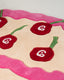 Close-up of a tuft rug with red cherries patterns on a beige background.