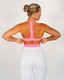 Person wearing a pink sports bra and grey pants on a plain background