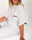 Person wearing a white t-shirt with brand logos on a plain background